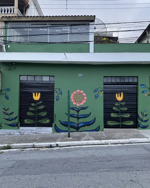 Green façade with painted flowers over black shutters